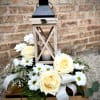 The highlight of this arrangement is the beautiful lantern. Roses and daisies