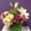 A high end low and compact arrangement of roses, lilies and hydrangeas.