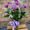6 beautiful lavender roses are arranged in a vase with filler flowers
