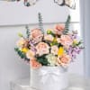 An elegant arrangement of blush roses, soft pastels, and fresh greenery in