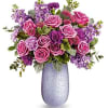 Bouquet features lavender roses, lavender and purple carnations, lavender stock, purple button