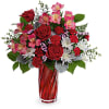 This bouquet features red roses, pink alstroemeria, miniature red carnations, white cushion