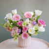 A light and airy composition featuring pastel pink roses, soft gerbera daisies