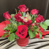 Red rose arrangement in a red barrel container, with a decorative butterfly.