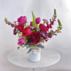 Jewel toned premium blooms professionally arranged in a white ceramic vase and