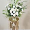 An all-white floral arrangement with carnations, snapdragons, roses, spidermums and greens, that