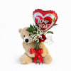 A sweet romantic gift featuring a plush teddy bear, a heart-shaped &ldquo;Love