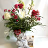 This red vase is filled with lilies, roses, carnations, mini carnations and