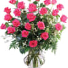 Two dozen long stem pink roses vased with greenery and filler.
