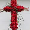 Cross of red roses embellished with bear grass and berries.....