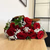 One dozen red roses with greenery and baby's breath. Wrapped in brown
