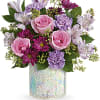 A cheerful mix of soft pink roses, lavender blooms, and vibrant purple