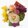 Roses orchids and more arranged in a modern glass cube vase. Pretty