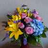 Designer's choice of blue hydrangea, yellow lilies, lavender roses, statice , and