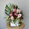 This floral arrangement features Shimmer roses, proteas, coffeeberries, and safari sunset, seeded
