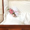 Heart-shaped satin casket pillow is adorned with a spray of pink roses