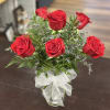 Red roses arranged in a clear glass vase with a white ribbon