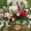 An elegant whimsical arrangement of pinks and mixed greens in a gold