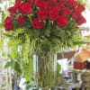 100 long stemmed red Roses in a glass vase with assorted foliage.