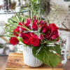Abundant array of red roses and tulips in a white ceramic pot