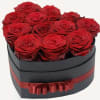This elegant heart-shaped white box arrangement of 12 red roses is a