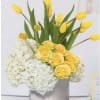White hydrangeas, yellow tulips  and yellow roses in a cub vase.