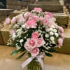 A pink and white round arrangement in a clear glass vase. This