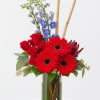 A artful display of Gerbera Daisies with Delphinium, Roses, exotic foliage's, and