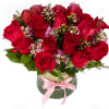 Red roses, wax flowers arranged in a glass vase.