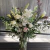 A tall cylinder vase filled with seasonal foliage, curly willow, cymbidium orchids