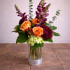This elegant vase is filled with a beautiful arrangement of purple and
