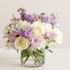 Fresh florals in pinks, lavenders, whites, and creams including greens and fillers.

*Vase/container