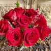A stunning arrangement of bright red roses, foliage, and fillers.