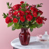 Amplified by a ruby red vase, this rich arrangement of roses, carnations