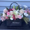 A designers choice gift bag, filled with colorful seasonal blooms. It will