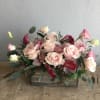 A wooden box of soft pink roses, calla lilies and textured greens