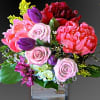 A fabulous arrangement of hot pink peonies, purple roses and tulips. Florist