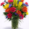 A bold and joyful floral arrangement designed in a clear glass cylinder