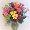 A designers choice of mixed bright flowers in a clear vase with