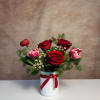 A classic red arrangement with red roses, tulips, and ranunculus in a
