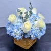 A soft and calming arrangement featuring lush blue hydrangeas paired with elegant