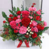 A charming mix of red and pink roses with lush greenery, elegantly
