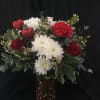 Bouquet of red and white flowers in a heart-decorated glass vase