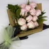 Bouquet of pale pink roses wrapped in gold paper with a green bow