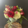 A beautiful modern pot filled with lush blooms like hydrangeas, roses, stock