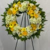 Vibrant sympathy wreath including creamy white Hydrangeas, yellow daisies, yellow Roses, and