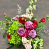 A lush blend of lavender roses, rich red carnations, green hydrangea, blush
