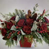 Red roses in a red glass cube with berries, pine cones, an