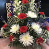 Red carnations, whiye spides, blue delphinium, white snapdragons, in blue glass cube.