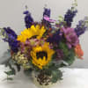 Sunflowers surrounded by orange roses, alstroemeria, and purple larkspur.